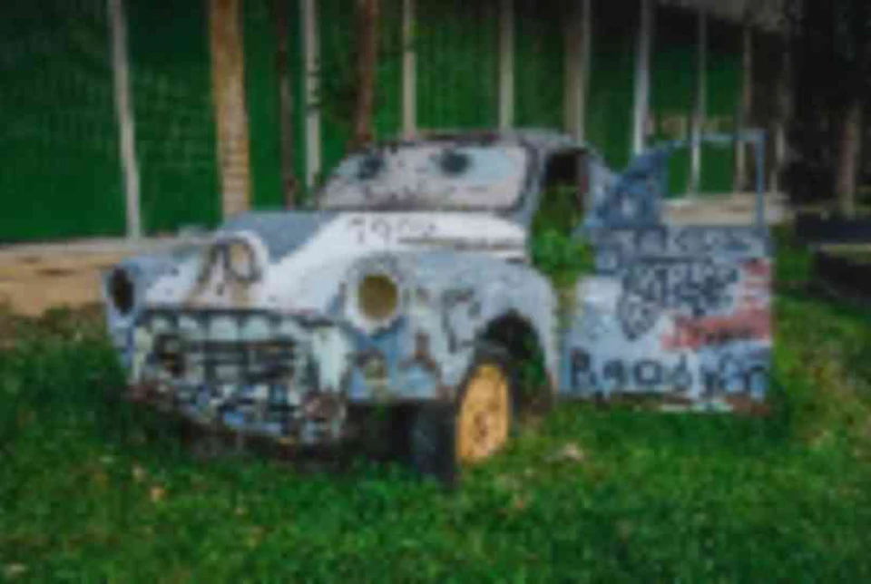 Blurry low-resolution photo of an abandoned car covered in graffiti